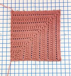 a crocheted square is sitting on a piece of fabric