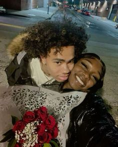 a man and woman hugging each other on the street with flowers in front of them