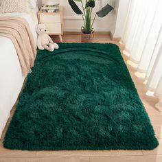 a large green rug in the middle of a bedroom with a teddy bear on it