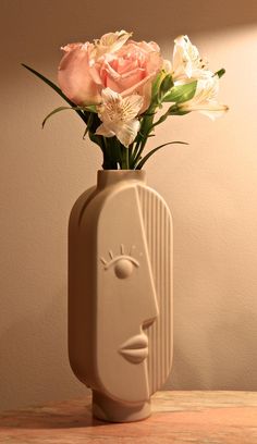 a vase with flowers in it sitting on a table next to a wall and a lamp