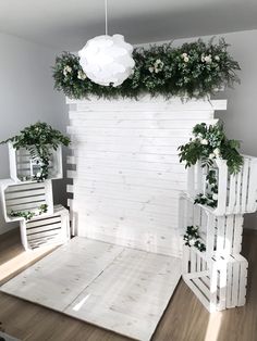 a room with white walls and plants on the wall, some chairs and a light fixture