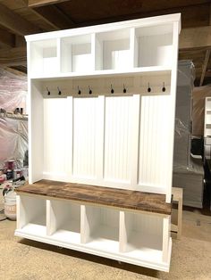 a white wooden bench sitting inside of a garage next to a wall mounted coat rack