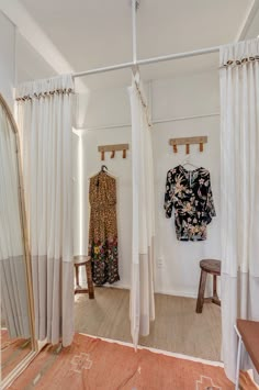 a room with curtains and clothes hanging on the wall