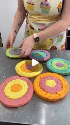 a woman is making cupcakes with colored frosting