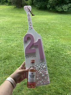 a person holding up a sign that says 21st birthday with a bottle of liquor in front of it