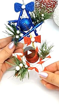 two hands holding christmas decorations on top of a white table with red, white and blue decorations