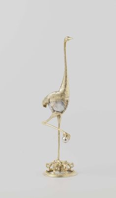 a gold plated figurine of a bird with a long neck and legs