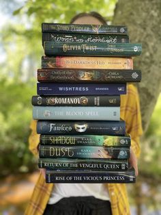 a stack of books stacked on top of each other in front of a person's face