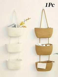 three baskets are hanging on the wall next to each other and one has a plant in it