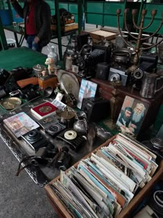 a table with many items on it and a man standing in the background looking at them