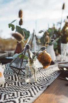 two vases filled with flowers sitting on top of a table next to plates and utensils