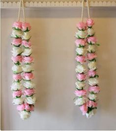 two pink and white flowers hanging from hooks