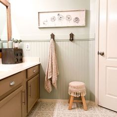 a small stool sits in the middle of a bathroom with a towel hanging on the wall