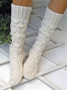 the legs of a woman wearing white knitted boots