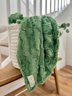 a green blanket sitting on top of a wooden bench