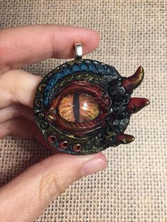 a hand holding a pendant with an eye in it