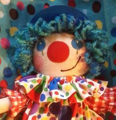 a clown doll with blue hair and polka dots on it's face sitting in front of a wall