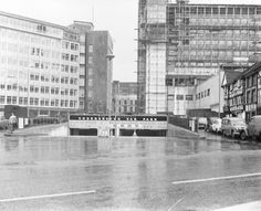 an old black and white photo of cars parked in front of tall buildings with scaffolding on them