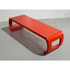 a red bench sitting on top of a cement floor