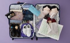 an open suitcase filled with clothes and other items on top of a purple surface next to a pair of shoes