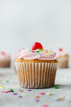 cupcakes with pink frosting and sprinkles on a white table