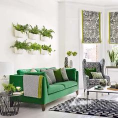 a living room with green couches and plants on the windowsills in it