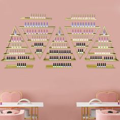 two pink chairs in front of a wall with shelves full of nail polish bottles on it