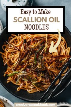 a bowl filled with noodles and vegetables on top of a blue tablecloth next to utensils