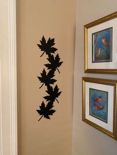 there is a wall decoration with leaves on it and two framed pictures next to it