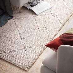 a living room area with a white couch, chair and book on top of the rug