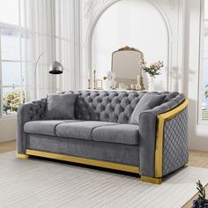 a living room with a gray couch and gold trim on the armrests, white carpeting and large windows