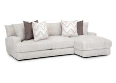 a white sectional couch with pillows on it's back and two different colored pillows