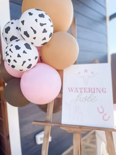 some balloons are on a wooden stand and there is a sign that says watering hole