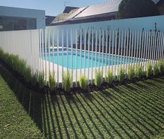 an empty swimming pool in the middle of a yard with grass growing around it and a white picket fence