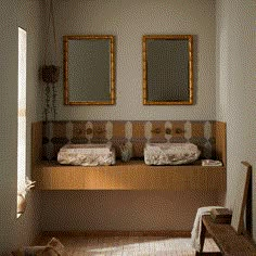 there are two sinks in the bathroom with mirrors on the wall above them and a bench to the side