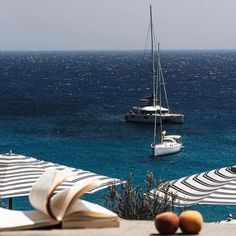 an open book sitting on top of a table next to some chairs and umbrellas