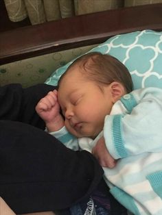 a baby sleeping on top of a blue and white blanket