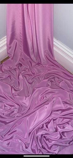 a bed covered in purple sheets and curtains