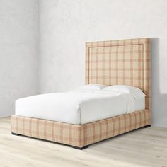 an upholstered bed with white sheets and plaid headboard