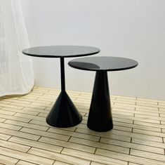 two black tables sitting on top of a wooden floor