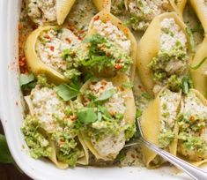 a white casserole dish filled with pasta and meat covered in guacamole sauce