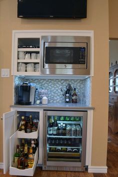 an open refrigerator with beer and soda in it next to a television mounted on the wall