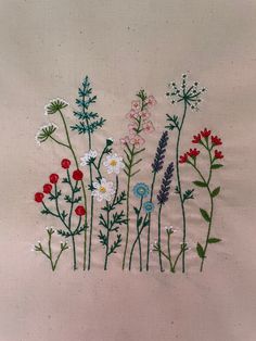 embroidered flowers on white linen with green stems and red, white, and blue flowers