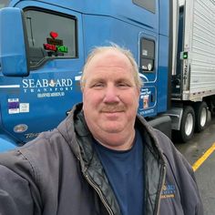 a man standing in front of a blue semi - truck with the seaboard logo on it