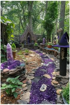 an outdoor garden with purple stones and rocks in the ground, surrounded by green trees