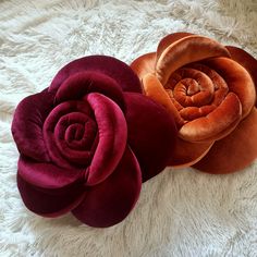 three different colored flowers sitting on top of a white blanket