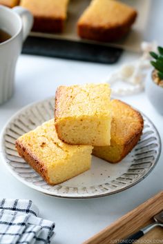 three pieces of cake on a plate next to a cup of tea