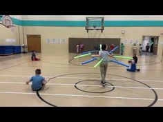 a group of people in a gym playing with lightsabens and basketball hoops