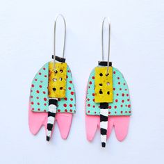 two pairs of earrings with colorful shapes and polka dots on them, hanging from hooks