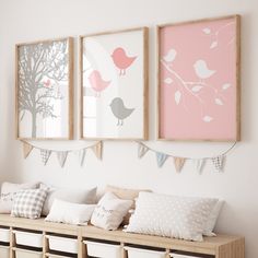 three framed pictures hang on the wall above a bench with pillows and baskets underneath them